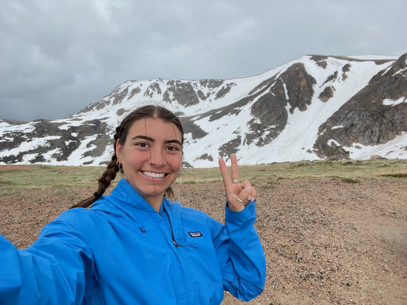 a person wearing a blue shirt standing in front of a mountain